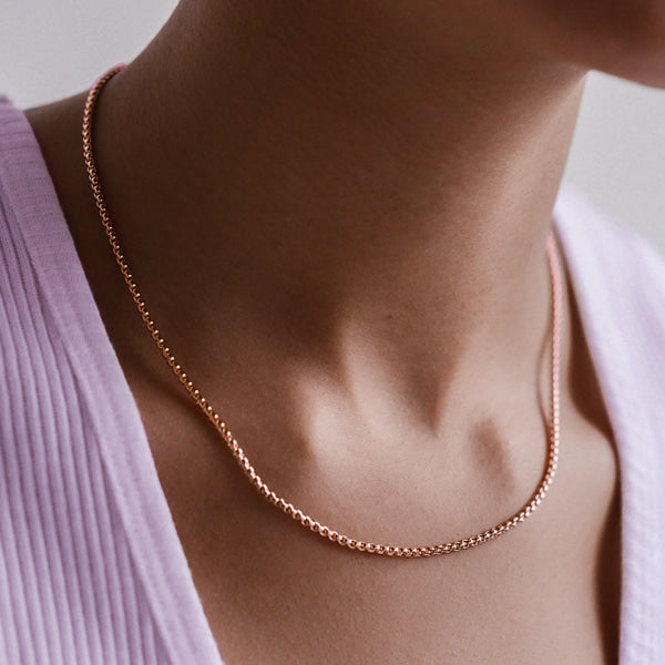 Woman wearing a 2mm rose gold box chain necklace on her neck