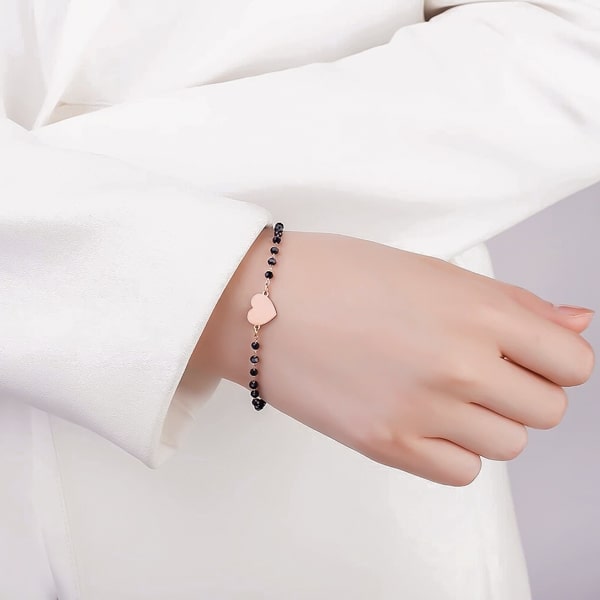 Woman wearing a black and rose gold beaded heart bracelet