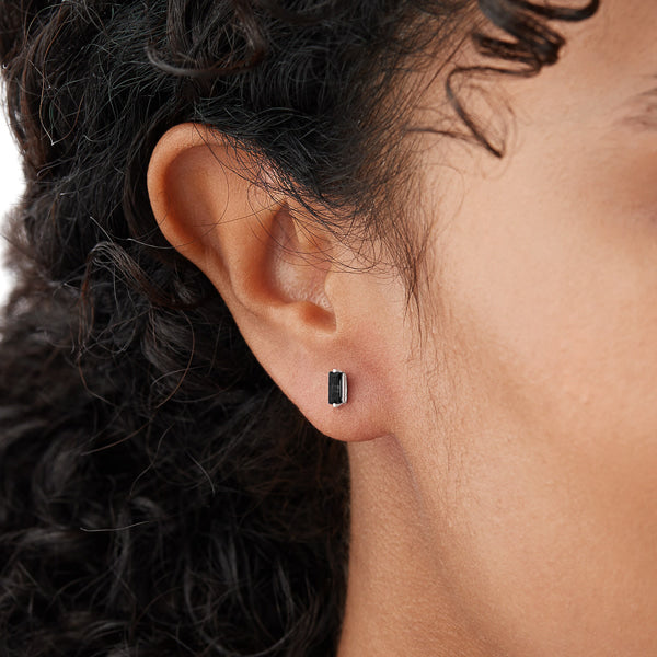 Woman wearing silver and black mini baguette stud earrings