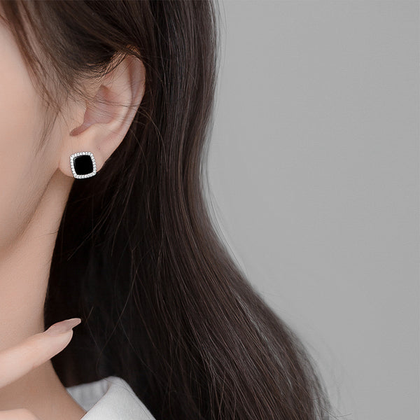Woman wearing black square cubic zirconia halo stud earrings