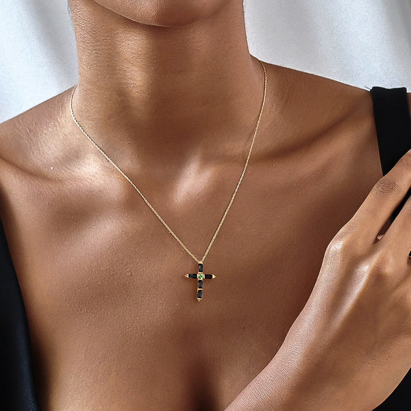 Woman wearing a black crystal cross on a gold necklace