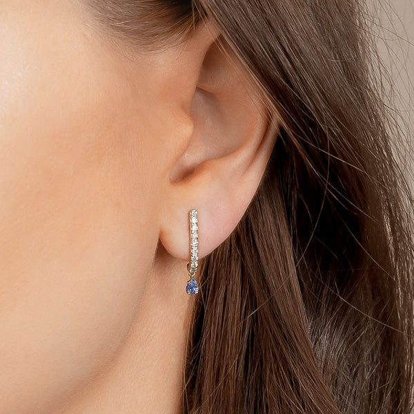 Woman wearing blue curved bar teardrop CZ earrings