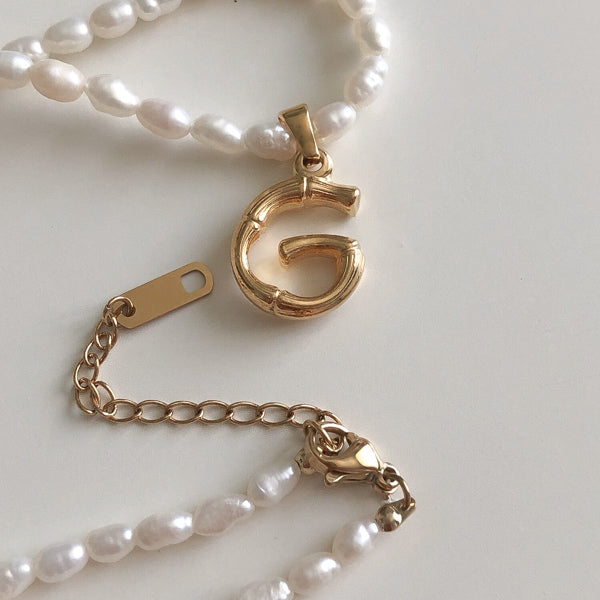 Freshwater pearl necklace with gold letter pendant, closeup photo