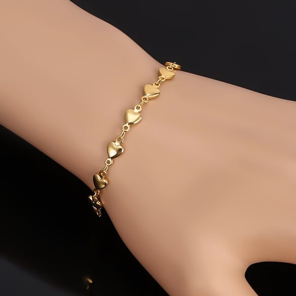 Woman wearing a gold heart chain bracelet on her wrist