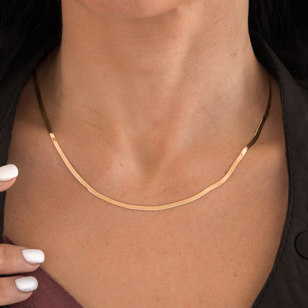 Woman wearing a 2mm gold herringbone chain necklace