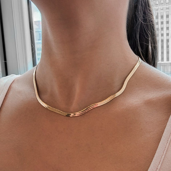Woman wearing a 4mm gold herringbone chain necklace