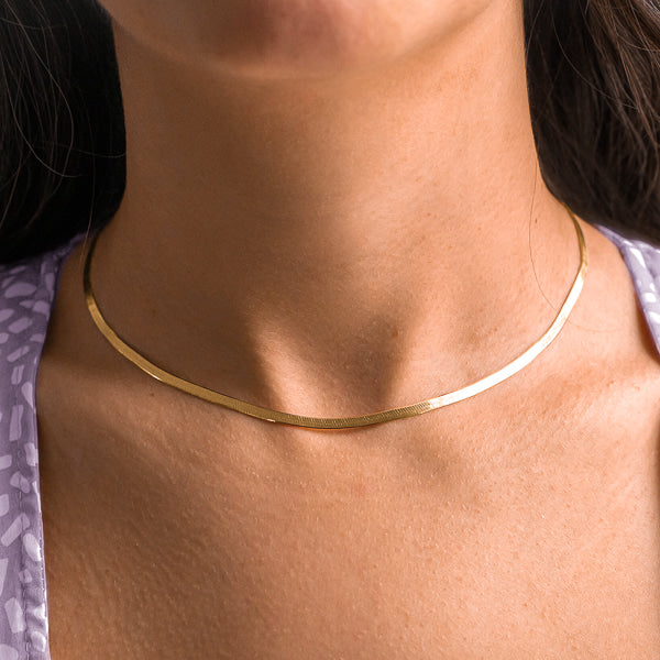 Woman wearing a gold herringbone choker necklace on her neck