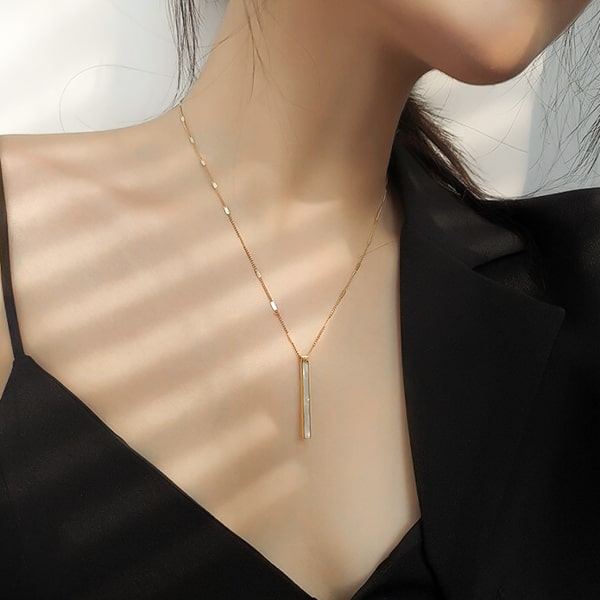 Woman wearing a gold pearly bar pendant necklace