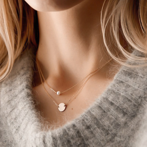 Woman wearing a gold layered pearl and coin necklace set