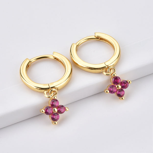 Gold huggie hoop earrings with a dangling pink cubic zirconia flower