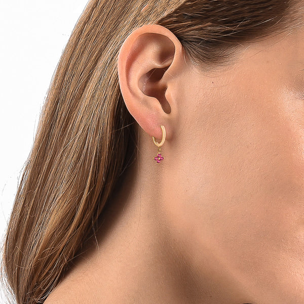 Woman wearing gold and pink mini flower huggie hoop drop earrings