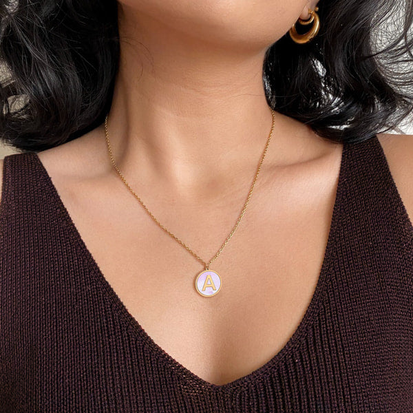 Woman wearing a gold and white round initial coin pendant necklace