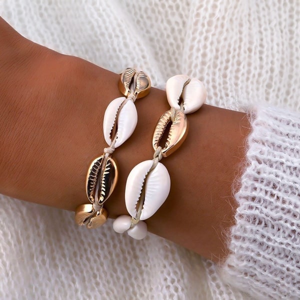 Gold and white cowrie shell bracelet on a woman's wrist
