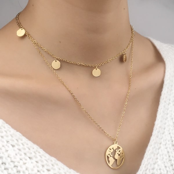 Woman wearing a gold layered world necklace with globe earth pendant