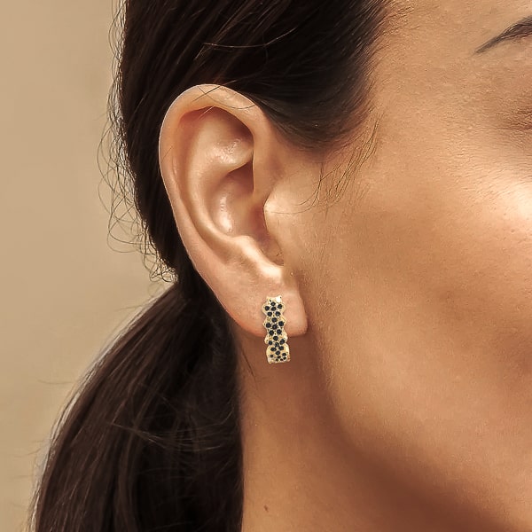 Woman wearing gold black flower pavé hoop earrings