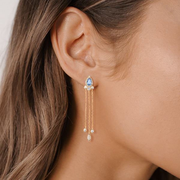 Woman wearing gold and blue crystal chandelier earrings