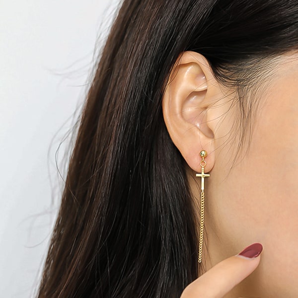 Woman wearing gold cross drop chain earrings