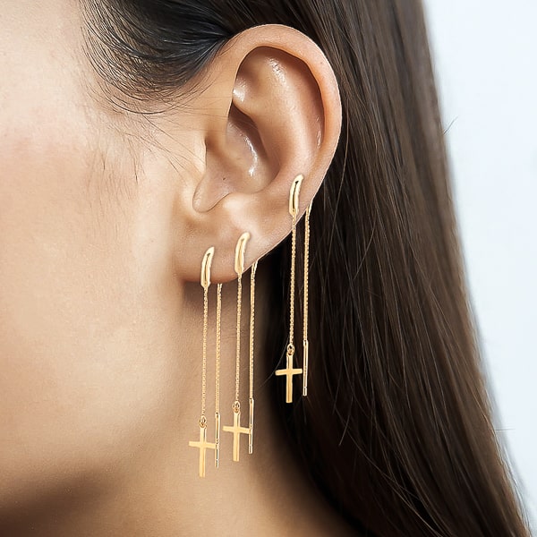 Woman wearing gold cross threader earrings