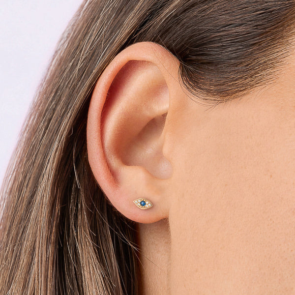 Woman wearing gold crystal eye stud earrings