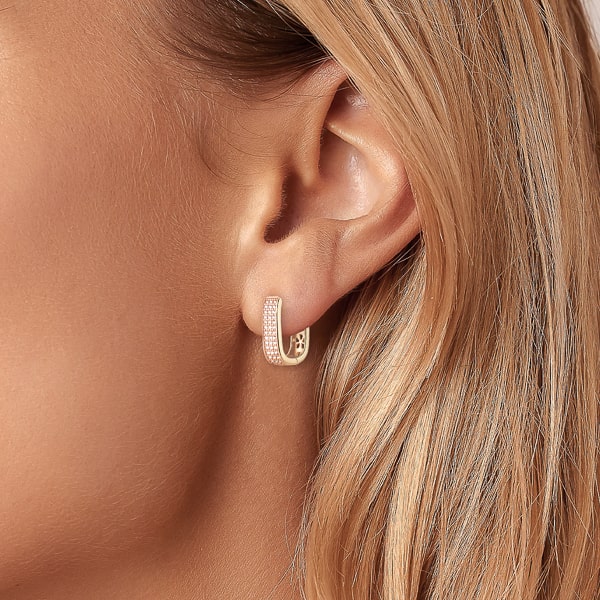 Woman wearing gold crystal pavé oval hoop earrings