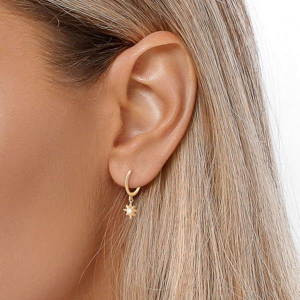 Gold crystal star mini hoop earrings on woman