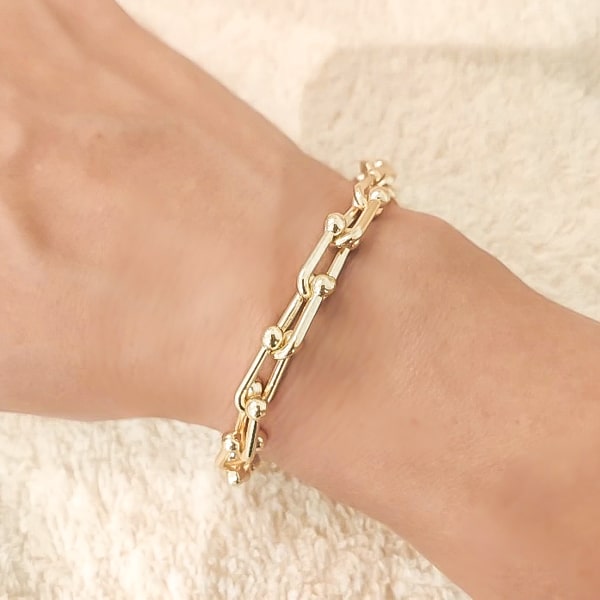 Gold designer link chain bracelet on a woman's wrist