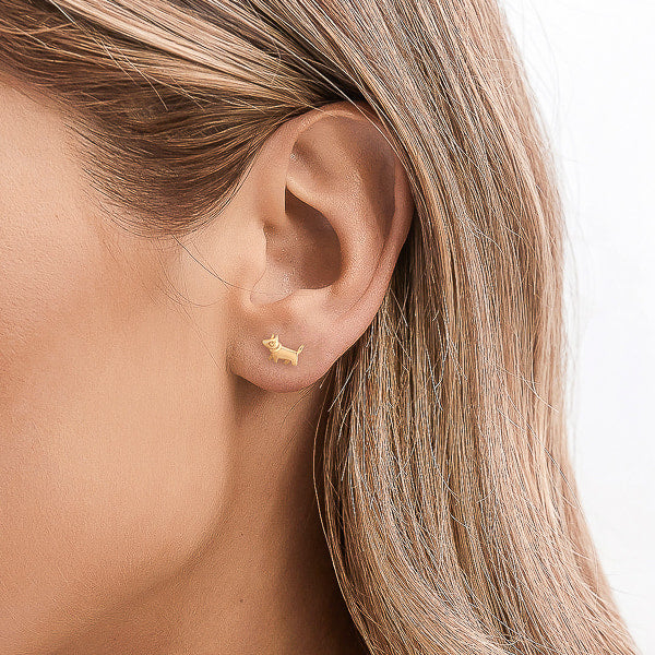 Gold dog stud earrings on model