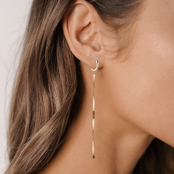 Woman wearing gold herringbone chain earrings