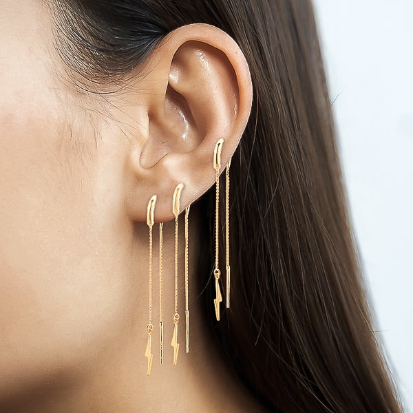 Woman wearing gold lightning bolt threader earrings