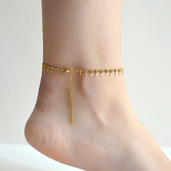 Gold lucky charm anklet on a woman's ankle