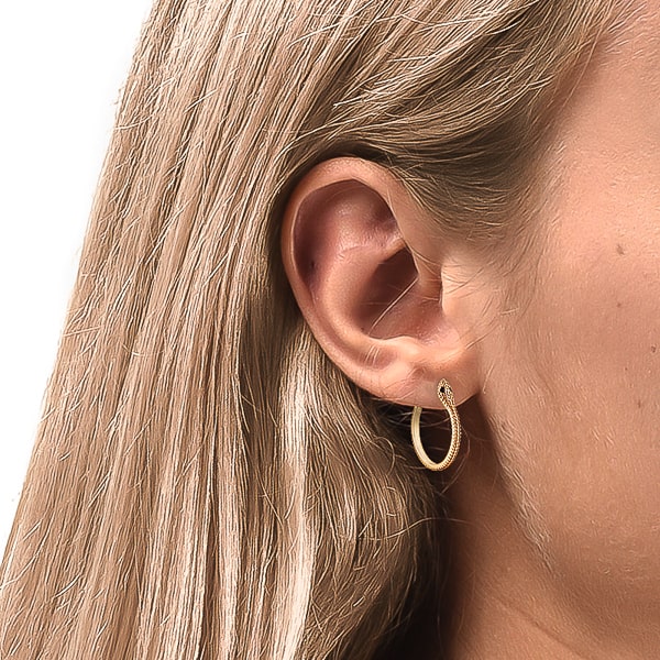 Woman wearing gold snake hoop earrings