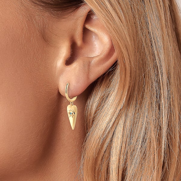 Woman wearing gold spear of luck huggie hoop earrings