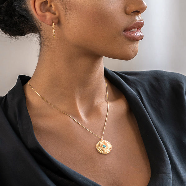 Woman wearing a gold sunset coin necklace