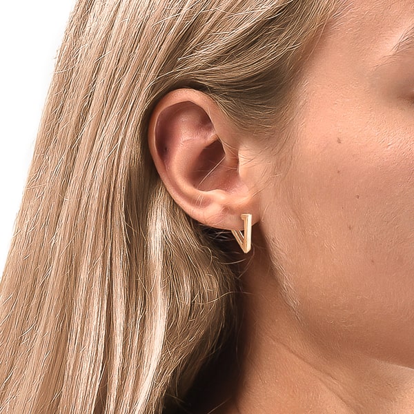 Woman wearing gold triangle huggie hoop earrings