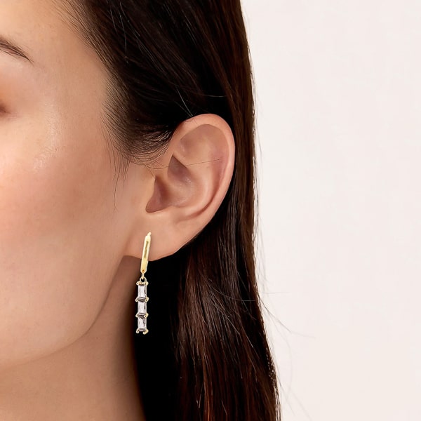 Woman wearing gold triple baguette bar drop hoop earrings