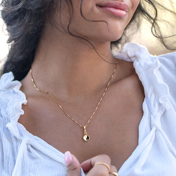 Woman wearing gold yin yang necklace