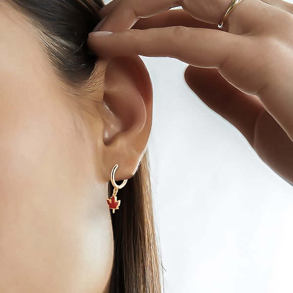 Woman wearing maple leaf mini hoop drop earrings