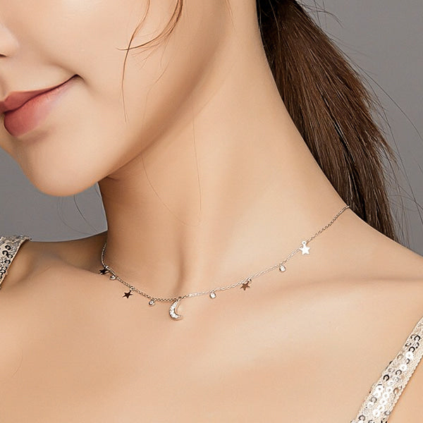 Woman wearing a sterling silver night sky necklace with moon and star pendants
