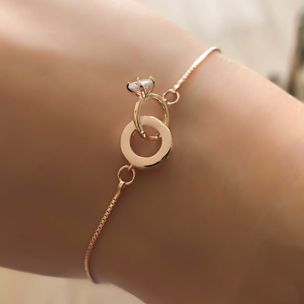 Rose gold engagement bracelet with two interlocking ring charms