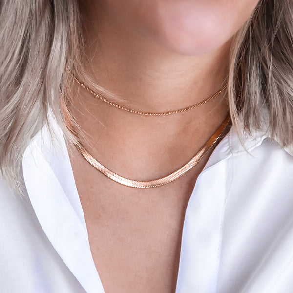 Woman wearing a 4mm rose gold herringbone chain necklace
