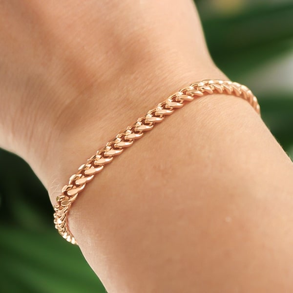 Rose gold Cuban link chain bracelet on a woman's wrist