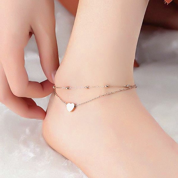 Rose gold layered beads and heart anklet on a womans ankle