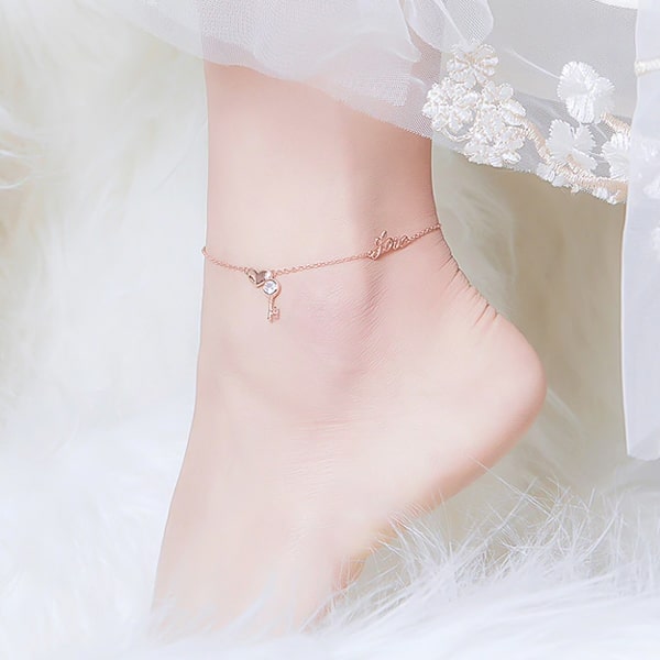 Rose gold 10K vermeil love anklet with a heart and a key pendant displayed on a womans ankle