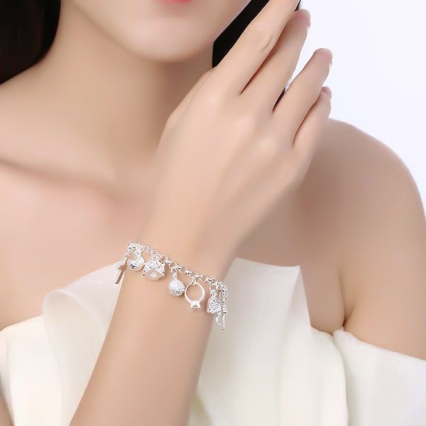 Silver charm bracelet on a womans wrist
