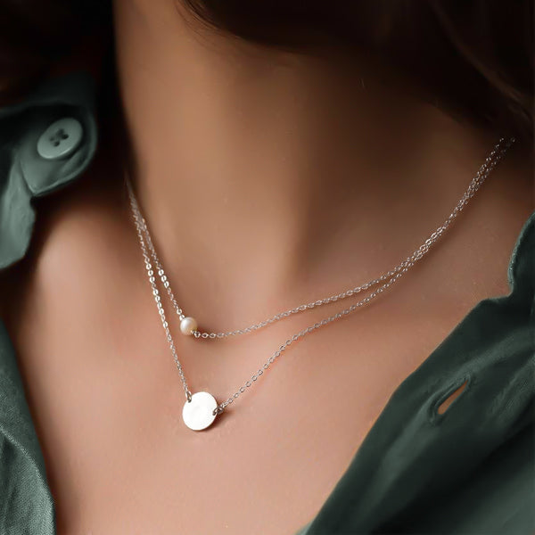 Woman wearing a silver layered pearl and coin necklace set