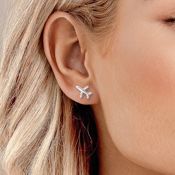 Woman wearing silver airplane stud earrings
