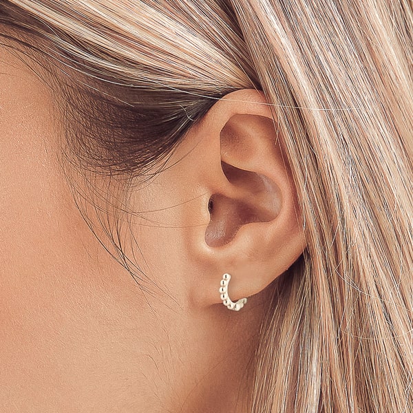 Woman wearing silver bead huggie hoop earrings