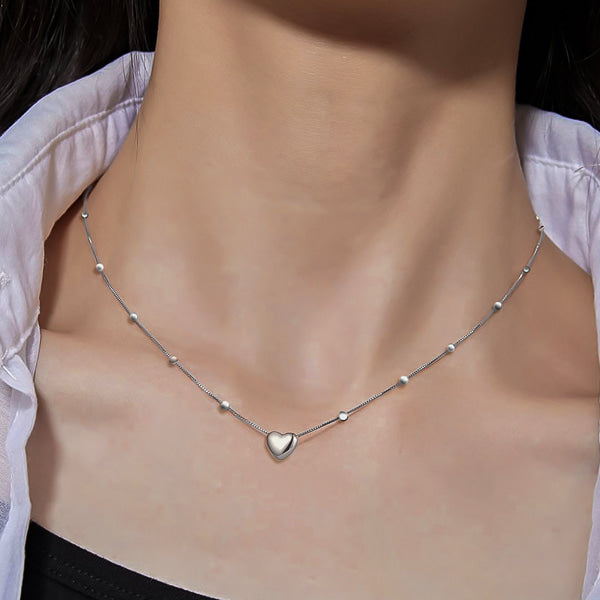 Woman wearing a silver beaded heart chain necklace