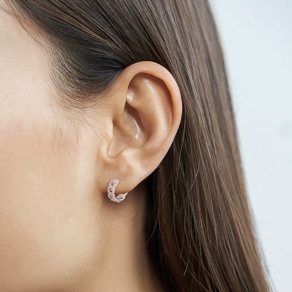 Woman wearing silver chain link huggie hoop earrings