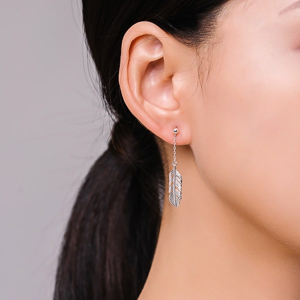 Woman wearing silver feather drop earrings